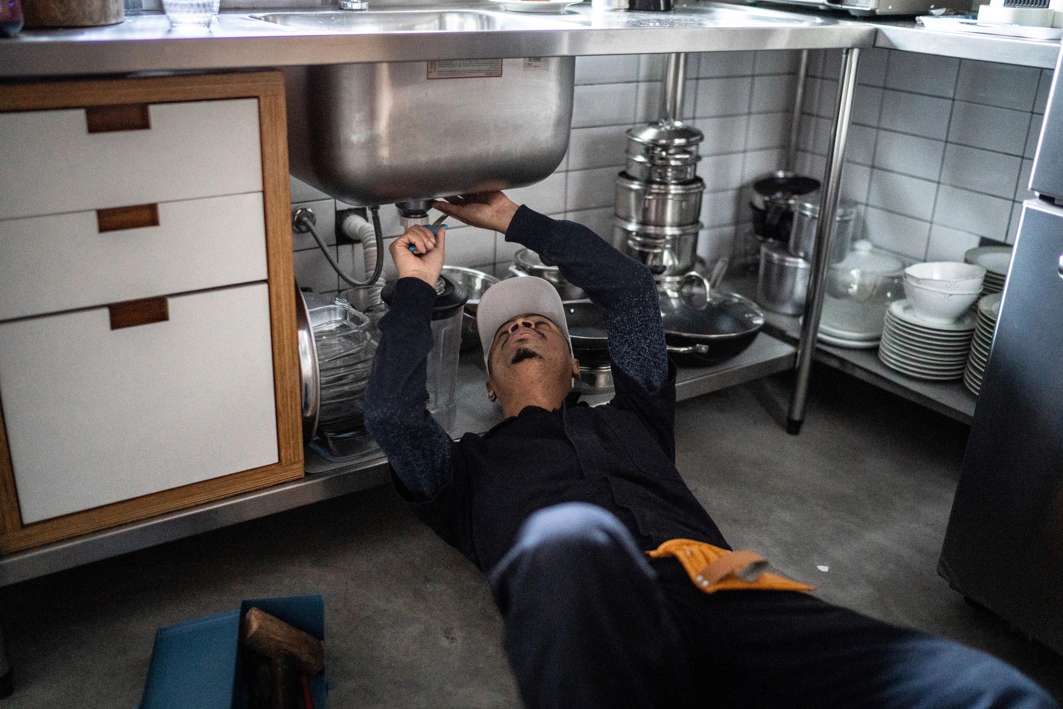 Plumber fixing water pipe under the sink
